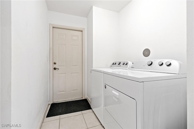 washroom featuring light tile patterned floors, baseboards, separate washer and dryer, and laundry area