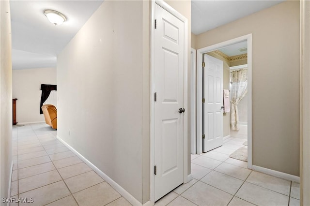 hallway with light tile patterned floors and baseboards