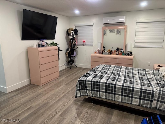 bedroom featuring recessed lighting, an AC wall unit, baseboards, and wood finished floors