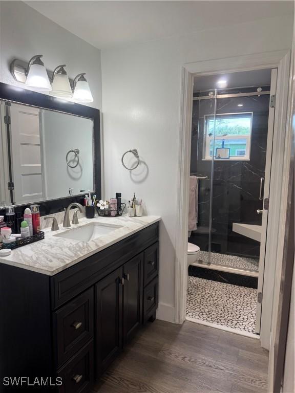 full bathroom featuring vanity, a shower stall, toilet, and wood finished floors