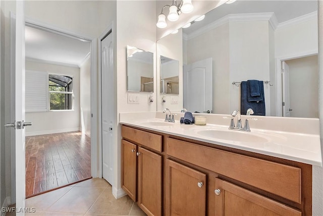 bathroom with tile patterned flooring, ornamental molding, double vanity, and a sink