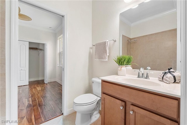 full bathroom with toilet, ornamental molding, vanity, and a tile shower