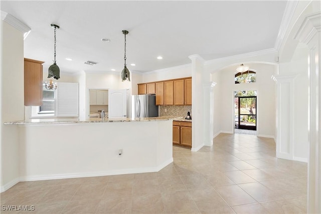 kitchen featuring crown molding, decorative backsplash, brown cabinets, freestanding refrigerator, and arched walkways