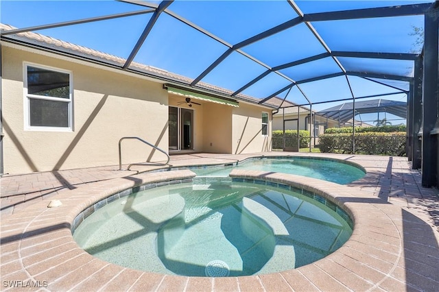 view of pool featuring a ceiling fan, glass enclosure, a patio area, and a pool with connected hot tub