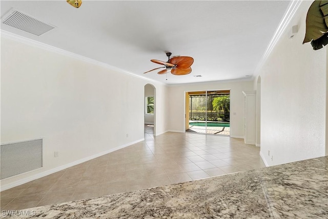 tiled spare room featuring crown molding, baseboards, visible vents, and ceiling fan