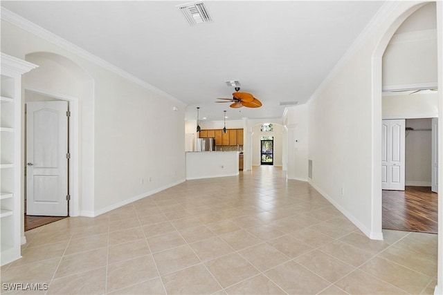 unfurnished living room featuring light tile patterned floors, built in shelves, visible vents, ceiling fan, and crown molding