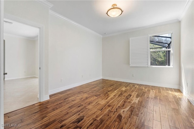 empty room featuring crown molding, wood finished floors, visible vents, and baseboards