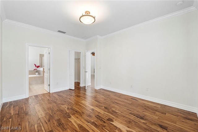 unfurnished bedroom featuring visible vents, ornamental molding, baseboards, and wood finished floors