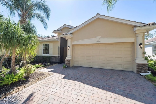 view of front of property with decorative driveway, a garage, stone siding, and stucco siding