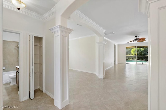 hallway featuring light tile patterned floors, arched walkways, ornate columns, and ornamental molding