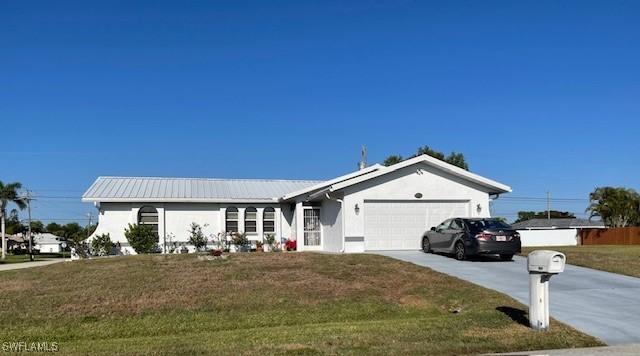 single story home with stucco siding, a front lawn, metal roof, concrete driveway, and a garage