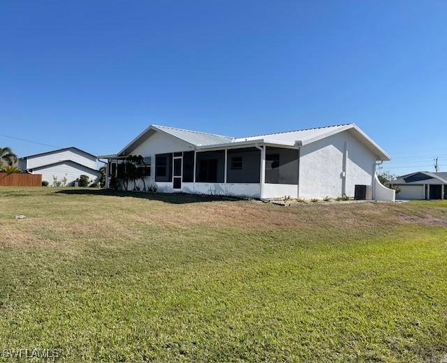 back of property with cooling unit, a lawn, a sunroom, and metal roof