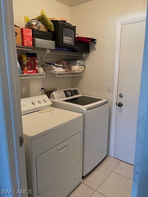 laundry room with washing machine and clothes dryer, laundry area, and light tile patterned flooring