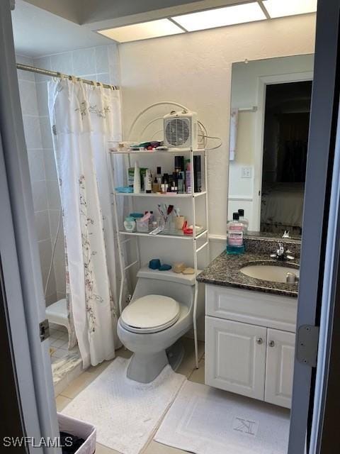 full bathroom featuring tiled shower, toilet, and vanity