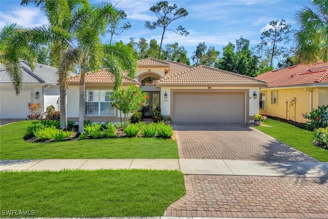 mediterranean / spanish-style home with an attached garage, stucco siding, a front lawn, a tile roof, and decorative driveway