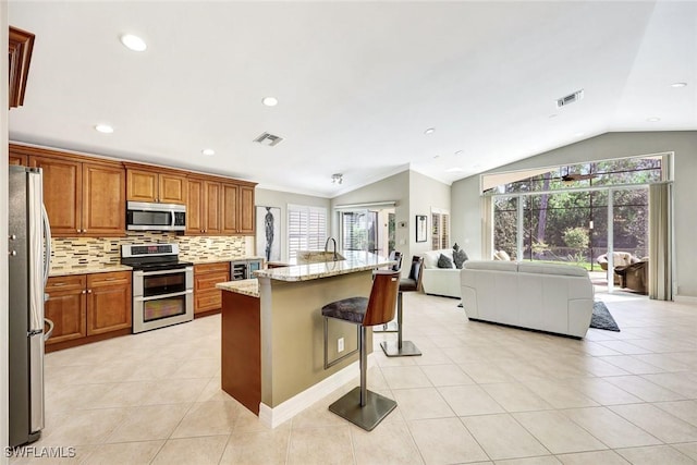 kitchen featuring light tile patterned floors, visible vents, open floor plan, appliances with stainless steel finishes, and tasteful backsplash