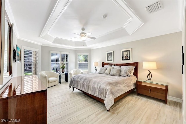 bedroom with a ceiling fan, visible vents, light wood finished floors, crown molding, and a raised ceiling