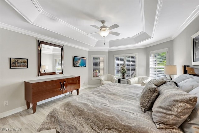 bedroom with baseboards, light wood finished floors, ceiling fan, ornamental molding, and a raised ceiling