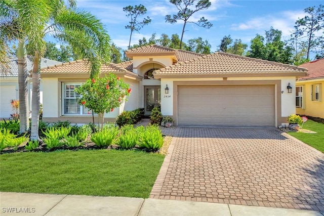 mediterranean / spanish-style home with stucco siding, decorative driveway, a front yard, a garage, and a tiled roof