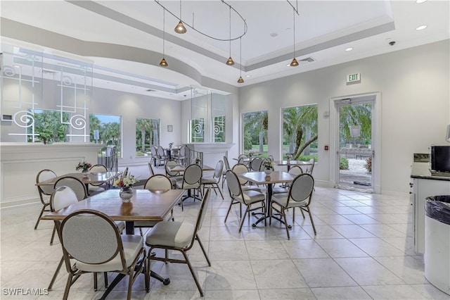 dining room with baseboards, visible vents, light tile patterned flooring, ornamental molding, and a raised ceiling