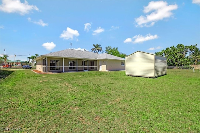 rear view of house featuring an outbuilding, a yard, a sunroom, and a storage unit