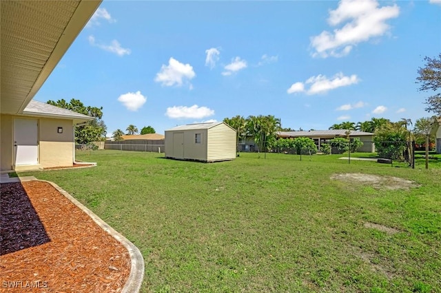 view of yard with an outbuilding, a storage unit, and fence