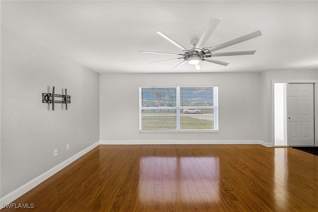 unfurnished room featuring a ceiling fan, wood finished floors, and baseboards