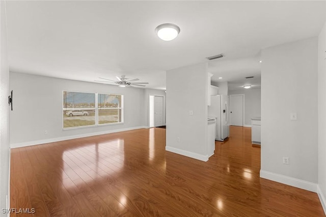 unfurnished living room with ceiling fan, baseboards, and wood finished floors