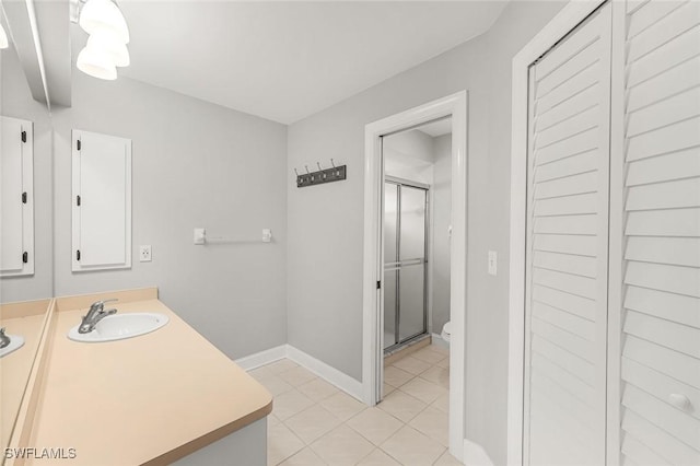 full bathroom featuring toilet, a shower stall, tile patterned flooring, baseboards, and vanity