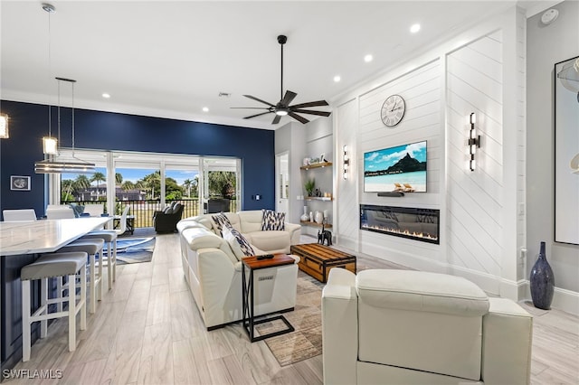 living room with visible vents, a ceiling fan, a glass covered fireplace, recessed lighting, and light wood-style floors