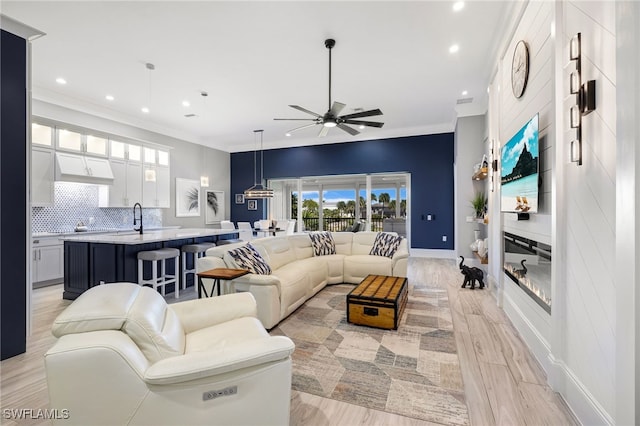 living room with light wood-style flooring, a ceiling fan, recessed lighting, a large fireplace, and baseboards