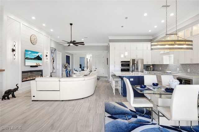 living area featuring visible vents, crown molding, light wood-type flooring, recessed lighting, and a ceiling fan