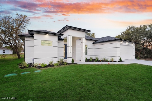 prairie-style house with concrete driveway, an attached garage, a yard, and stucco siding