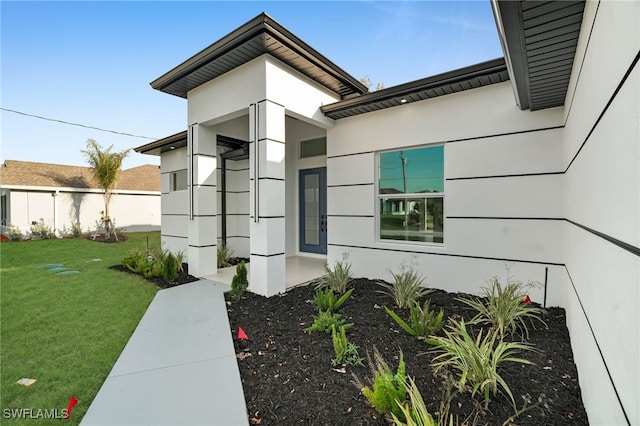 doorway to property with a lawn, fence, and stucco siding