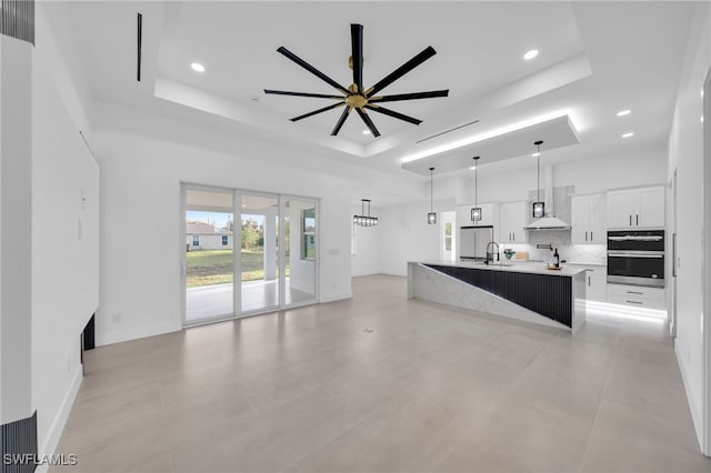 kitchen with a ceiling fan, a tray ceiling, a sink, white cabinetry, and backsplash