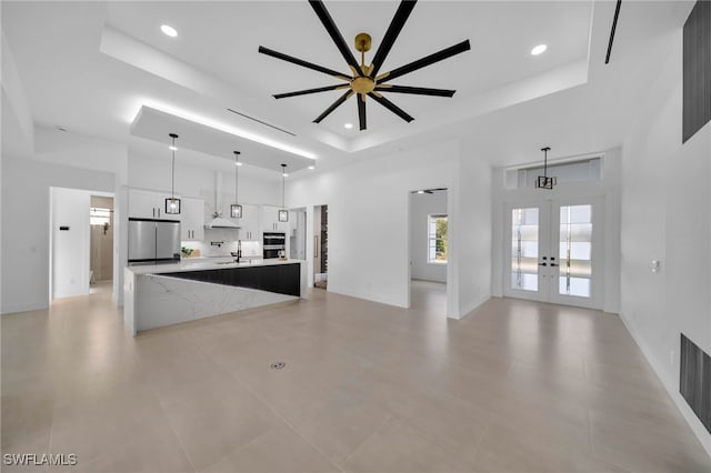 kitchen featuring a sink, a tray ceiling, french doors, and freestanding refrigerator