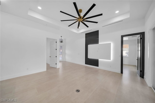 unfurnished room with a tray ceiling, recessed lighting, and baseboards