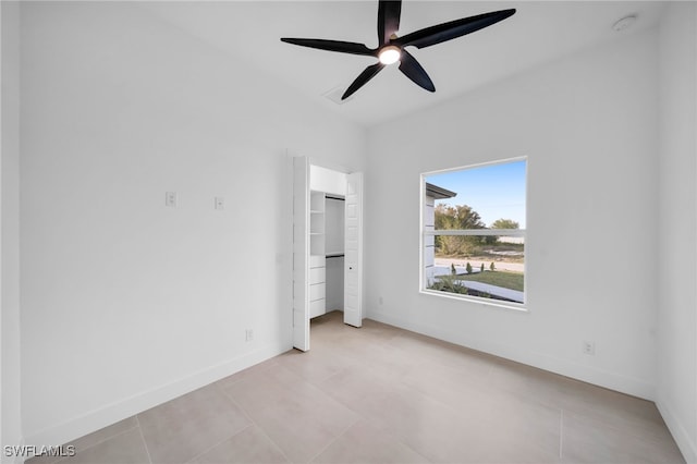 unfurnished bedroom with light tile patterned floors, ceiling fan, and baseboards