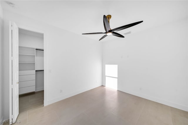 unfurnished bedroom with visible vents, baseboards, a walk in closet, and ceiling fan