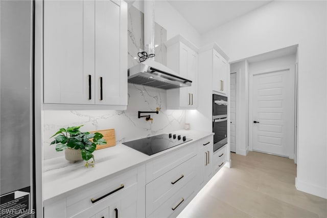 kitchen with light countertops, white cabinets, black electric stovetop, wall chimney exhaust hood, and tasteful backsplash