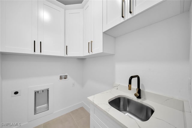 clothes washing area featuring electric dryer hookup, washer hookup, a sink, cabinet space, and light tile patterned floors