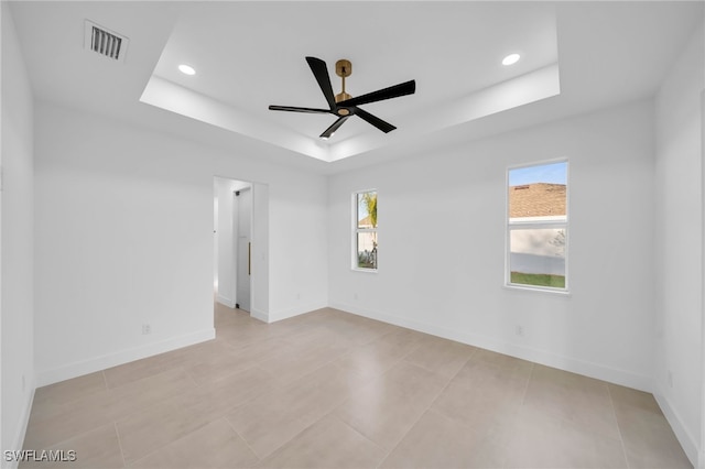 unfurnished room with a tray ceiling, plenty of natural light, baseboards, and visible vents