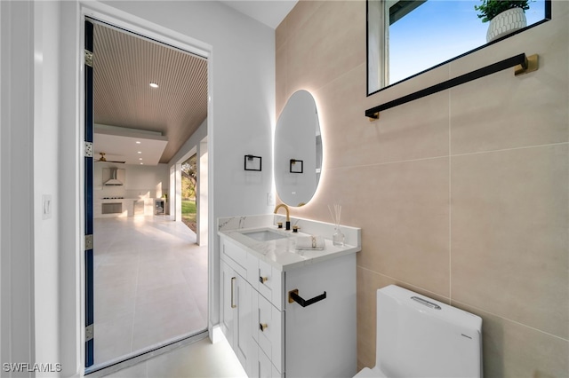 bathroom featuring vanity, recessed lighting, tile walls, toilet, and tile patterned floors