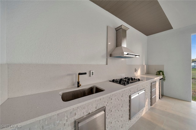 kitchen featuring light countertops, gas cooktop, wall chimney range hood, and a sink