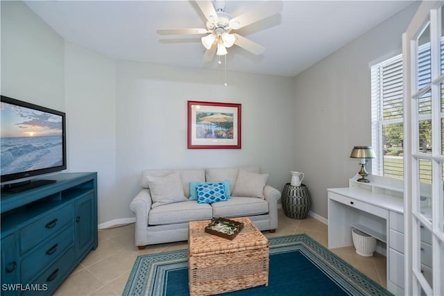 living room with light tile patterned floors, baseboards, and a ceiling fan