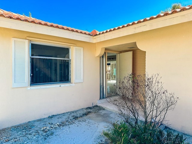 entrance to property with stucco siding and a tile roof