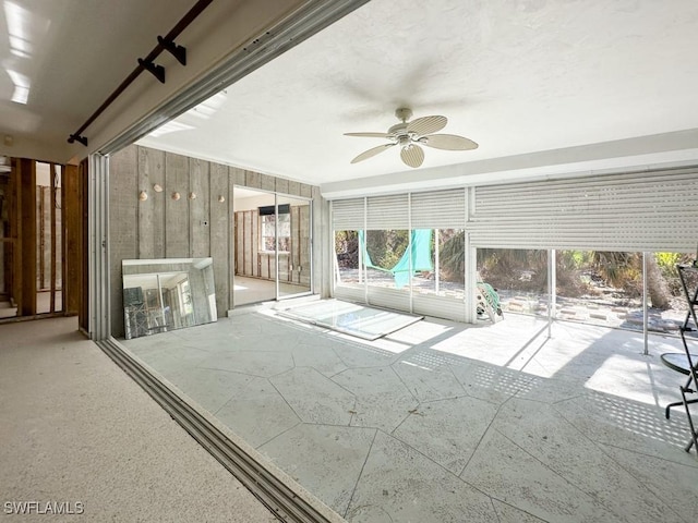 unfurnished sunroom with ceiling fan