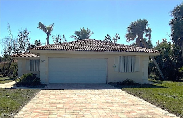 view of front of house with stucco siding, a tile roof, decorative driveway, a front yard, and a garage