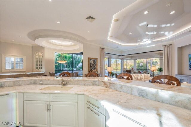 29115 W Teramo Way, Naples, FL 34110 - kitchen with light stone countertops, a sink, a raised ceiling, a ceiling fan, and ornamental molding