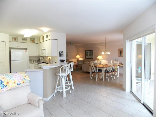 kitchen with open floor plan, white appliances, a peninsula, light tile patterned flooring, and light countertops